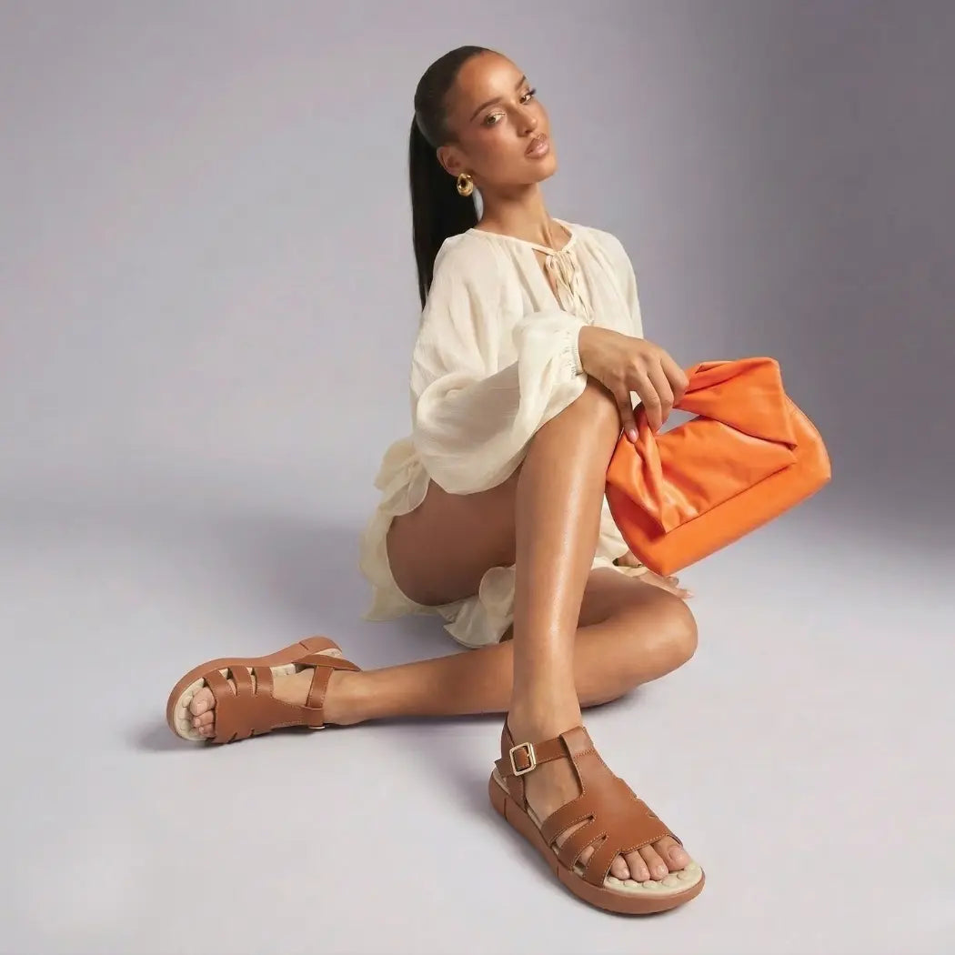 Modelo sentada usando sandália ortopédica feminina Calira™ bege