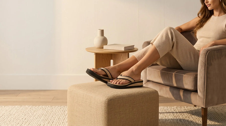 Mulher usando chinelo massageador ortopédico feminino para relaxar os pés em ambiente acolhedor