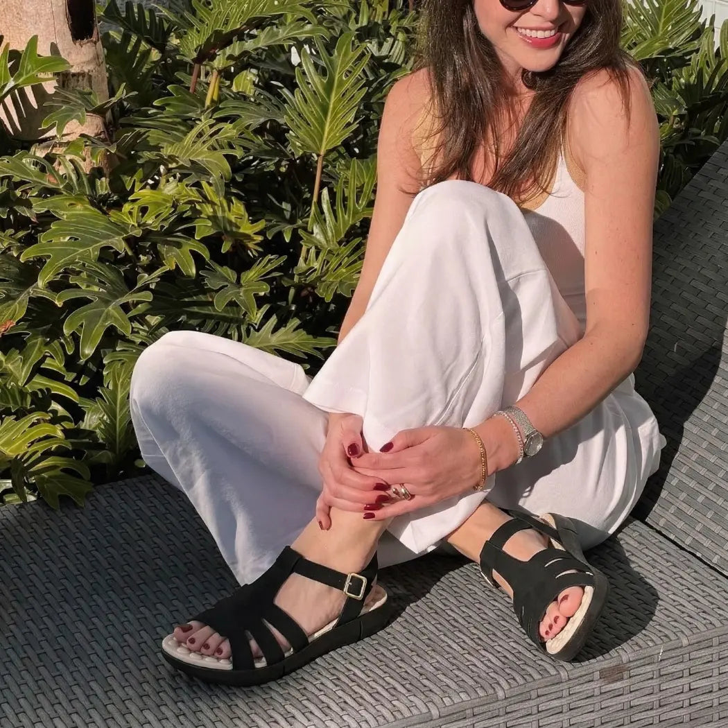 Modelo sentada usando sandália ortopédica feminina Calira™ preta
