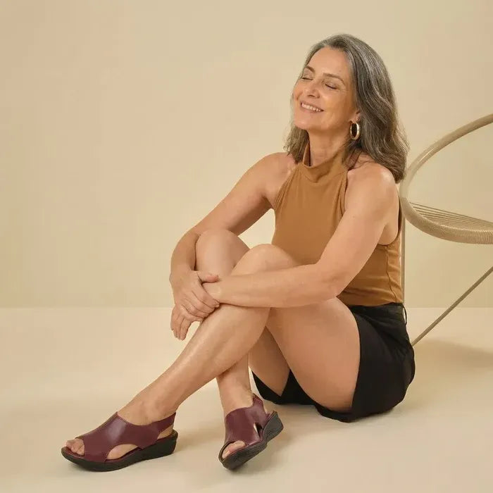 Modelo sentada usando sandália ortopédica feminina vinho